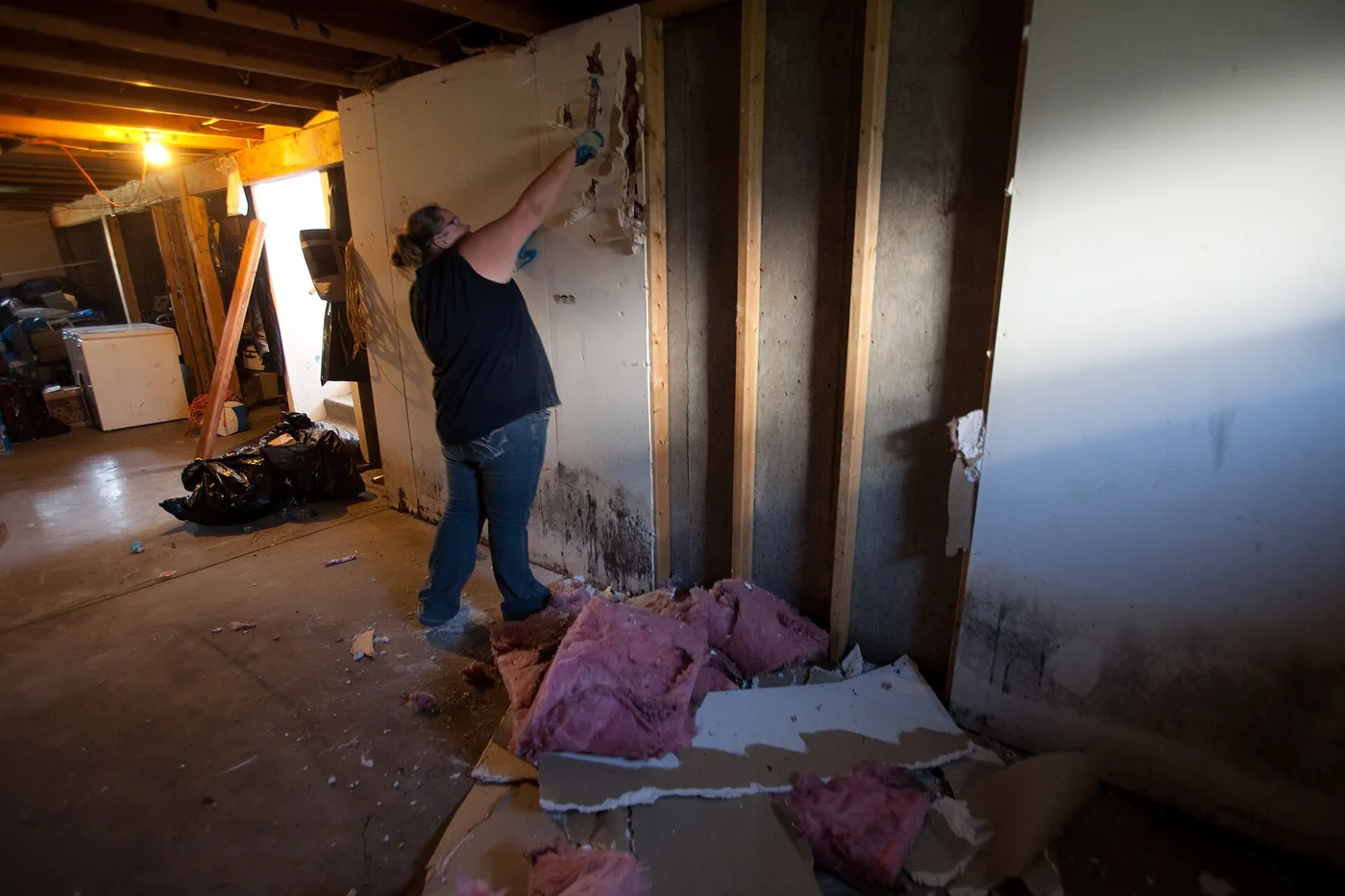 Worker removing wet drywall after a flood