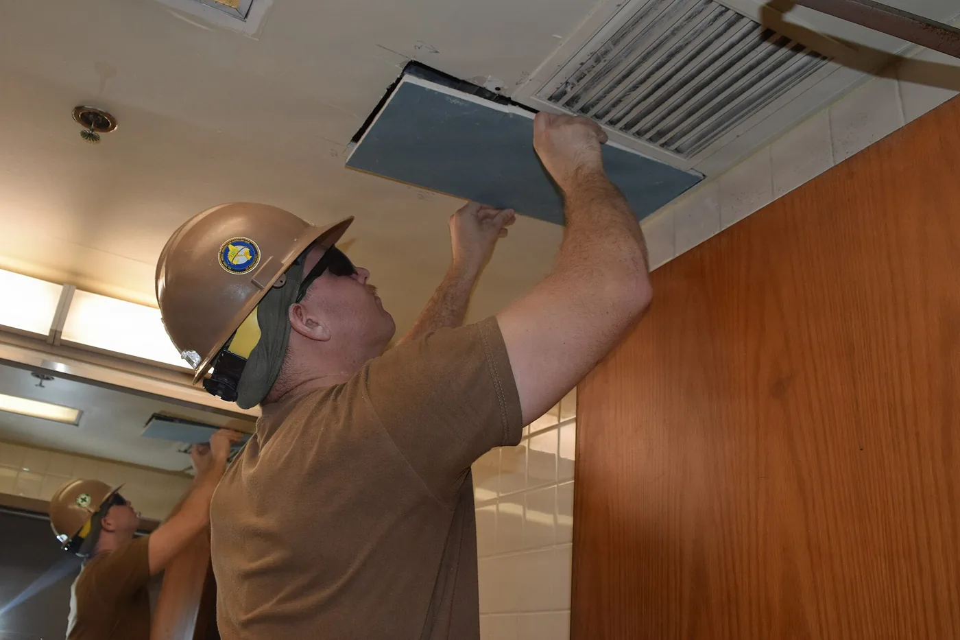 Worker installing a ceiling panel in a commercial space